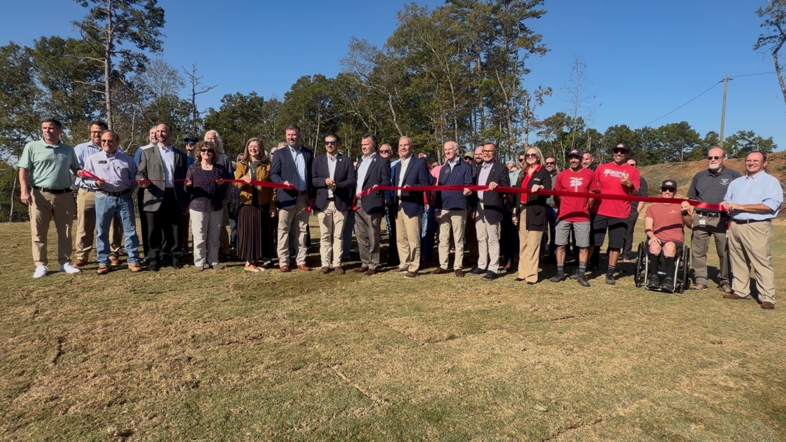 image of 20+ attendees holding a ribbon 